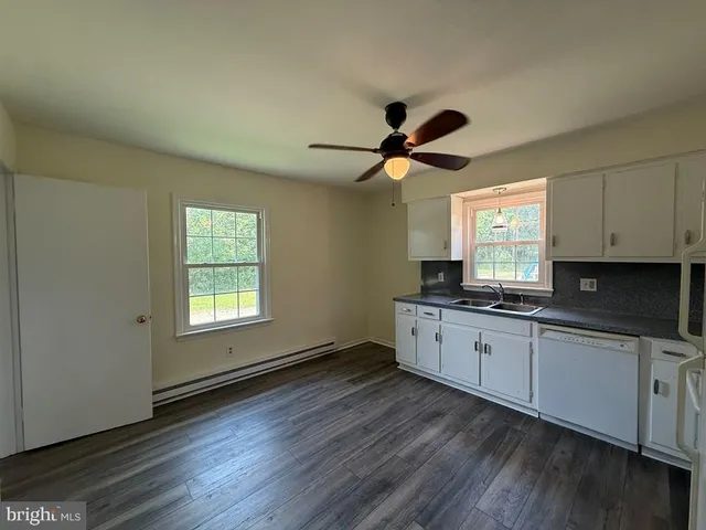 a large kitchen with cabinets wooden floor and a window