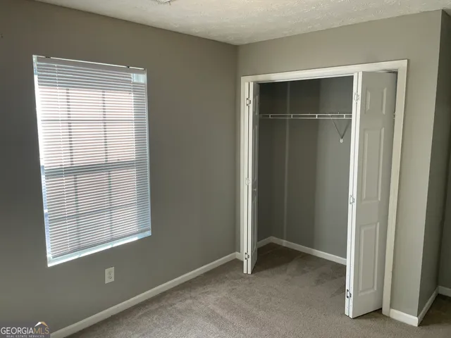 a view of an empty room with closet and a window