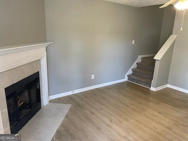 a view of an empty room with wooden floor fireplace and a window