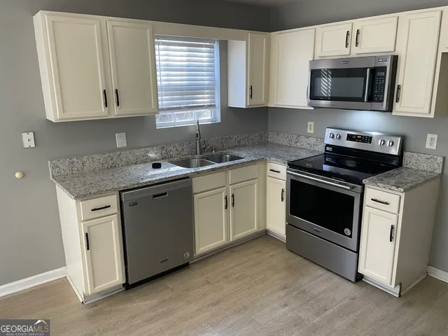 a kitchen with cabinets stainless steel appliances a sink and a microwave