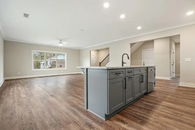 a kitchen with kitchen island granite countertop a sink cabinets and wooden floor