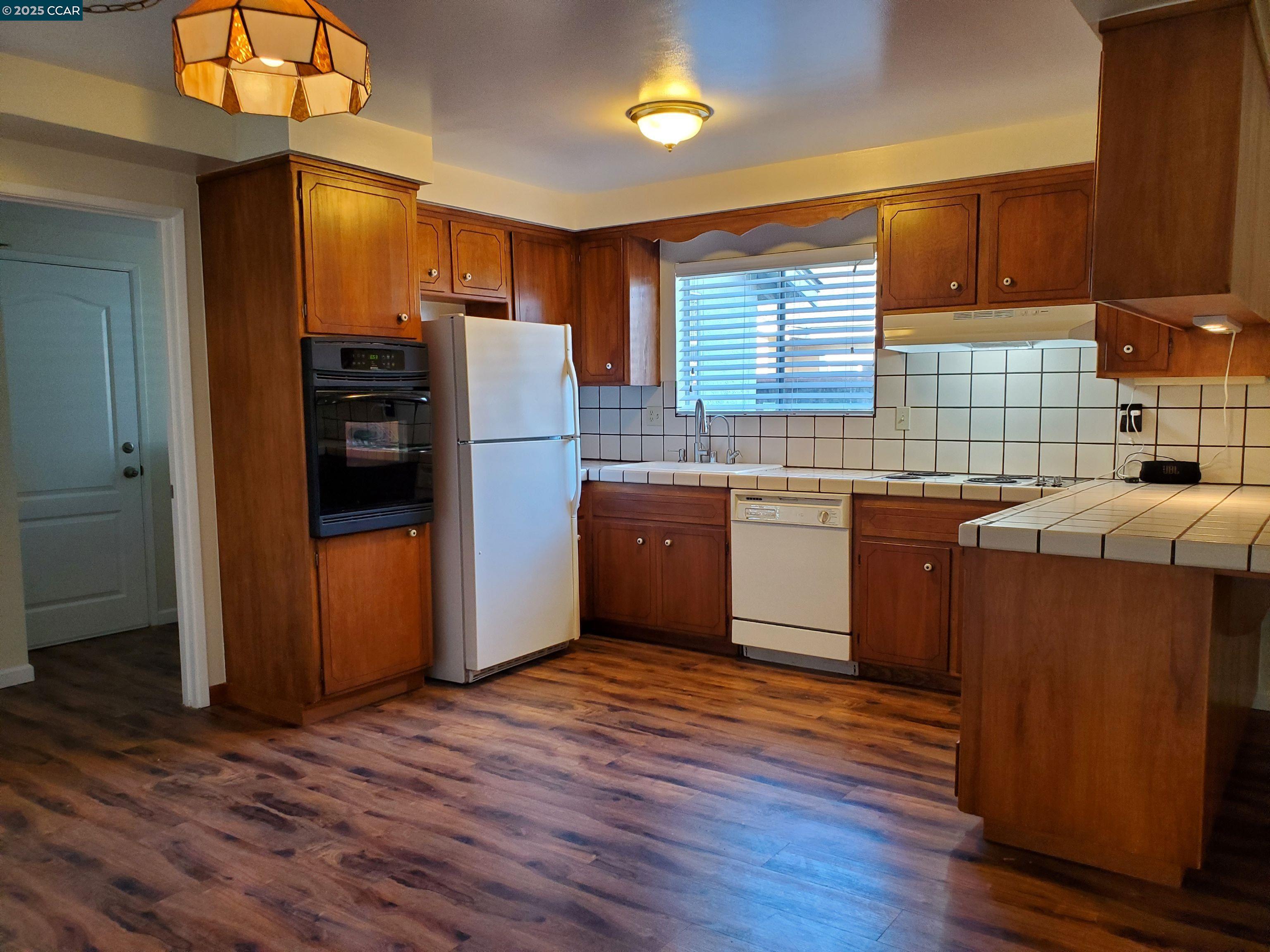 1616 Eve Drive Concord, CA 94521 - Photo 26 of 28 a kitchen with stainless steel appliances granite countertop a refrigerator a sink dishwasher a stove with wooden floor and cabinets
