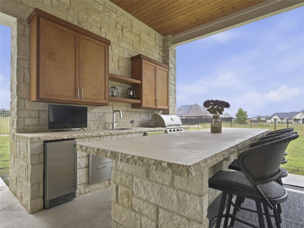 4211 Azalea Way Midlothian, TX 76065 - Photo 39 of 39 Outdoor kitchen featuring stone construction, wood cabinetry, a built-in stainless steel grill, and an integrated refrigerator