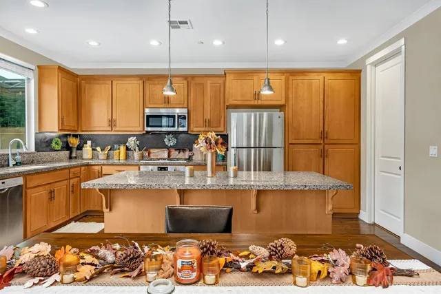 a kitchen with stainless steel appliances granite countertop a refrigerator a stove and a sink with wooden floor