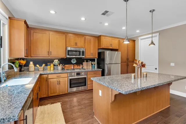a kitchen with stainless steel appliances granite countertop a stove a sink and a microwave