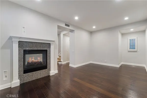 a view of an empty room with wooden floor fireplace and a window