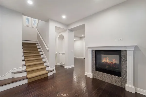 a view of an empty room with wooden floor and stairs