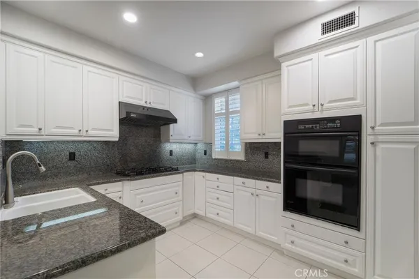 a kitchen with granite countertop white cabinets and stainless steel appliances