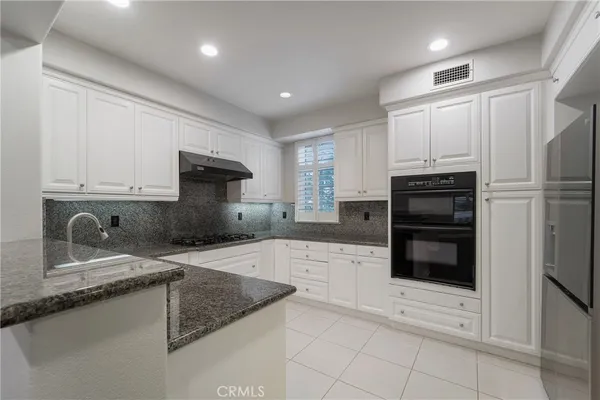 a kitchen with granite countertop a refrigerator sink and cabinets