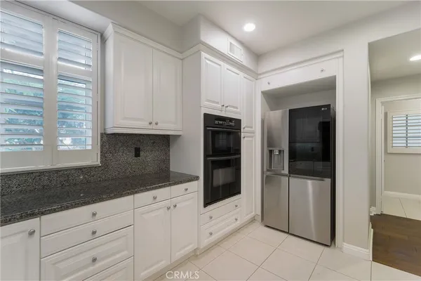 a kitchen with granite countertop white cabinets and refrigerator