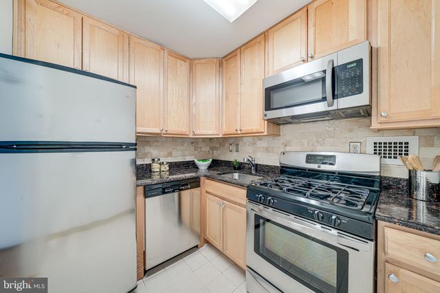a kitchen with stainless steel appliances granite countertop white cabinets sink and a granite counter top