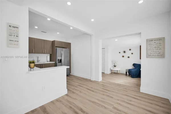 a living room with stainless steel appliances furniture a refrigerator and a view of kitchen