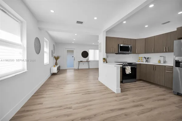 a open kitchen with kitchen island a sink dishwasher a stove and a refrigerator with wooden floor