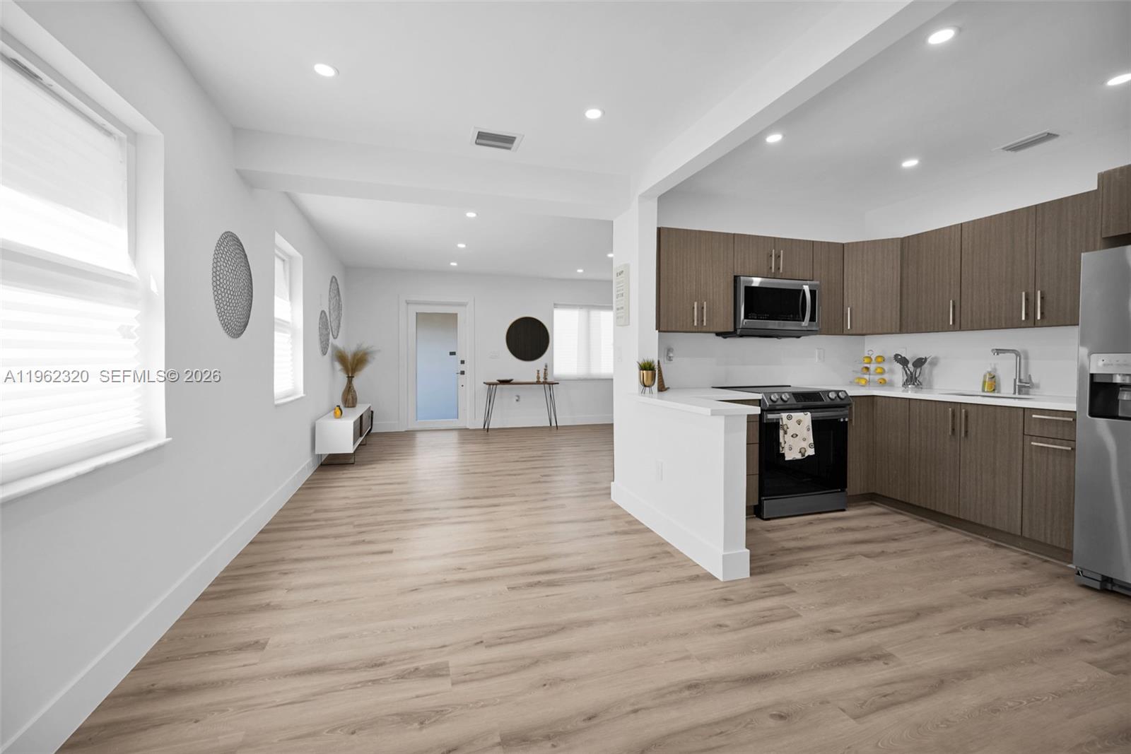 6540 Southwest 4th Street, Unit 6540 Miami, FL 33144 - Photo 23 of 42 a open kitchen with kitchen island a sink dishwasher a stove and a refrigerator with wooden floor