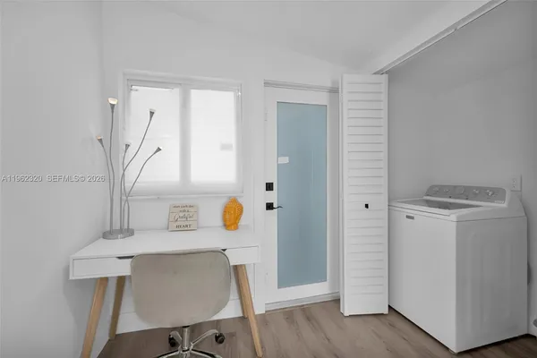 a view of a hallway to room with wooden floor and cabinet