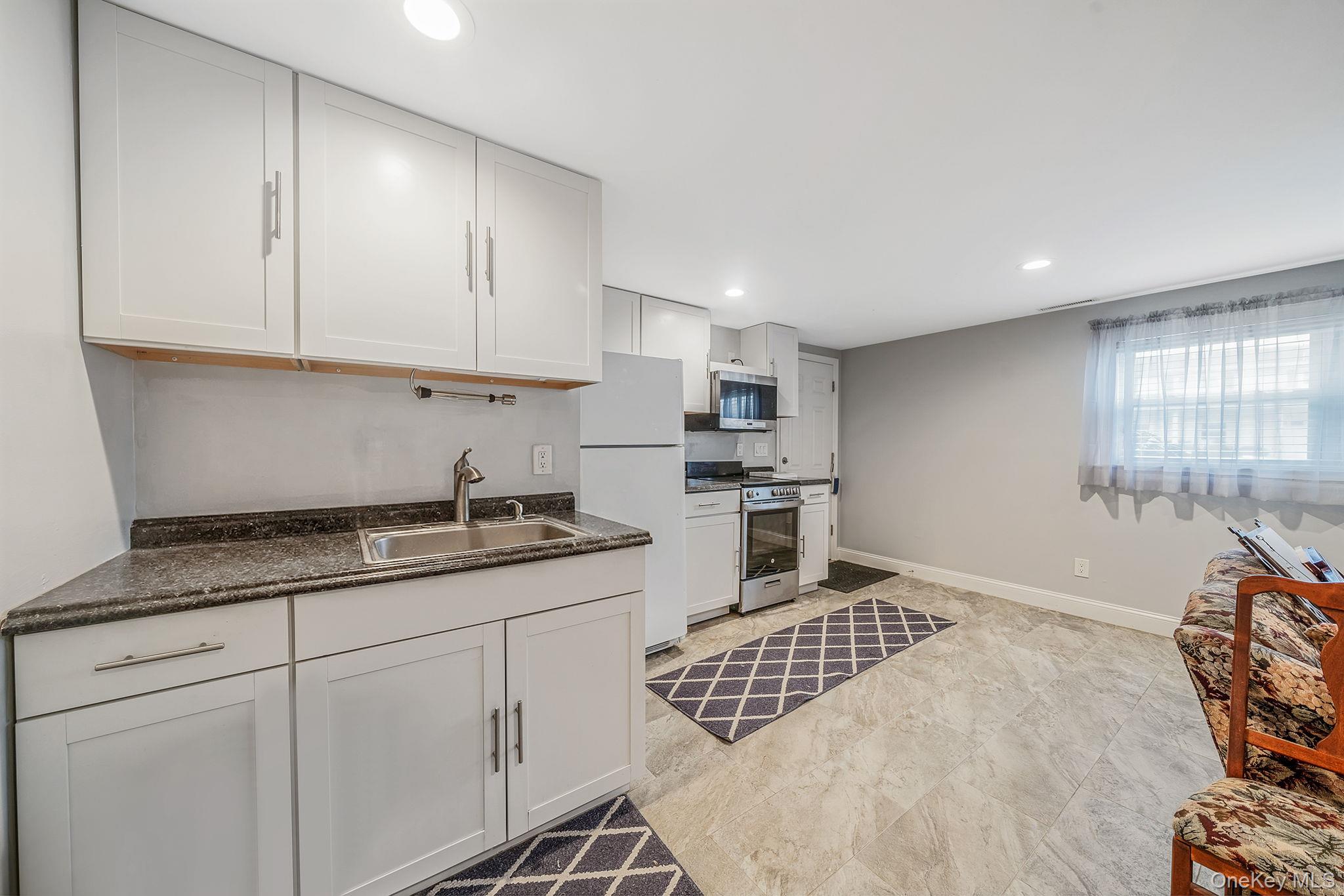 110 Stephen Road Bayport, NY 11705 - Photo 33 of 39 a kitchen with granite countertop a sink a stove and cabinets