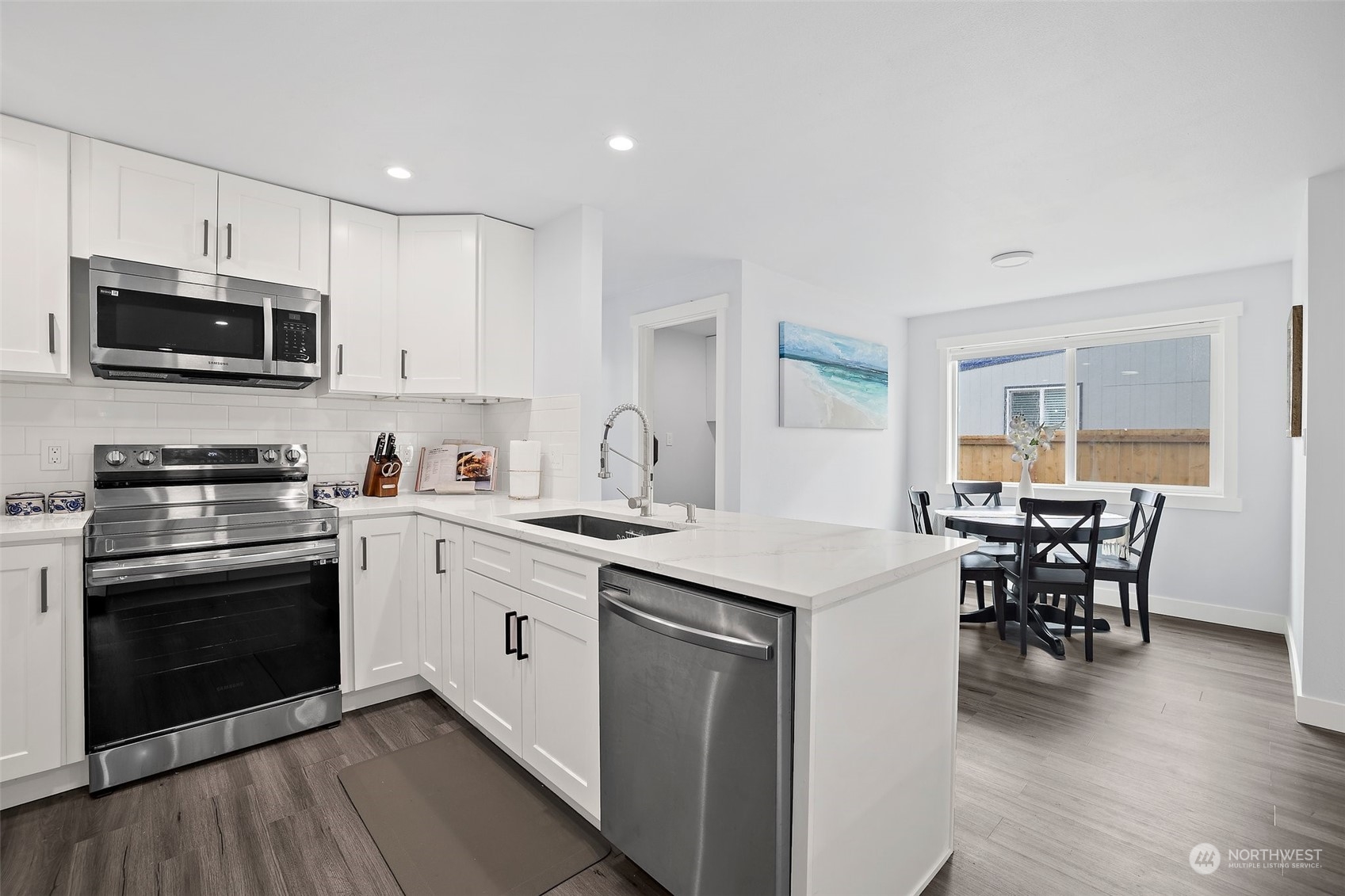 9848 18th Avenue Southwest Seattle, WA 98106 - Photo 9 of 32 a kitchen with stainless steel appliances granite countertop a stove a sink a microwave a dining table and chairs with wooden floor