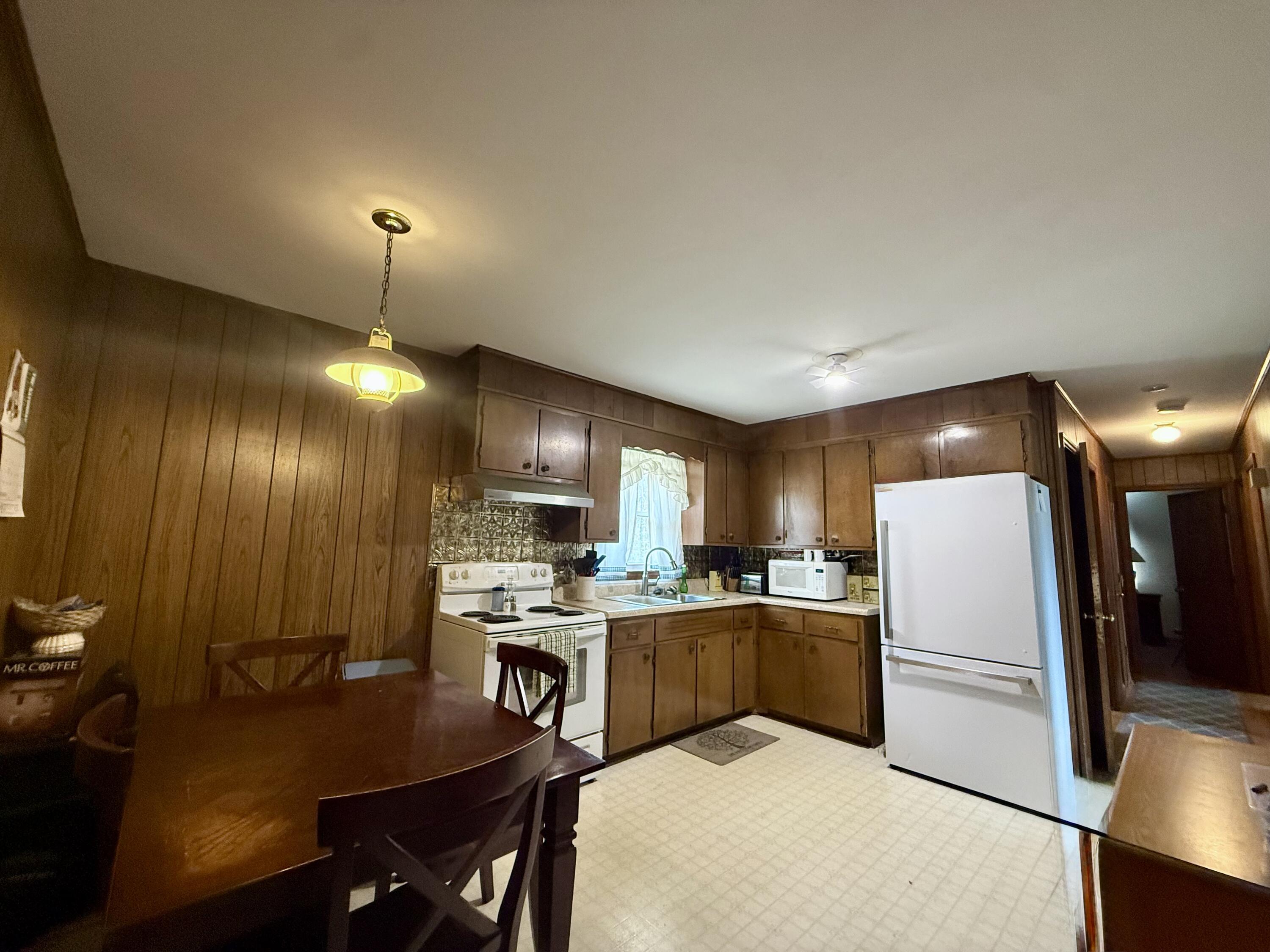 755 Goldmine Road Glade Hill, VA 24092 - Photo 5 of 13 a kitchen with a refrigerator a stove a sink a dining table and chairs