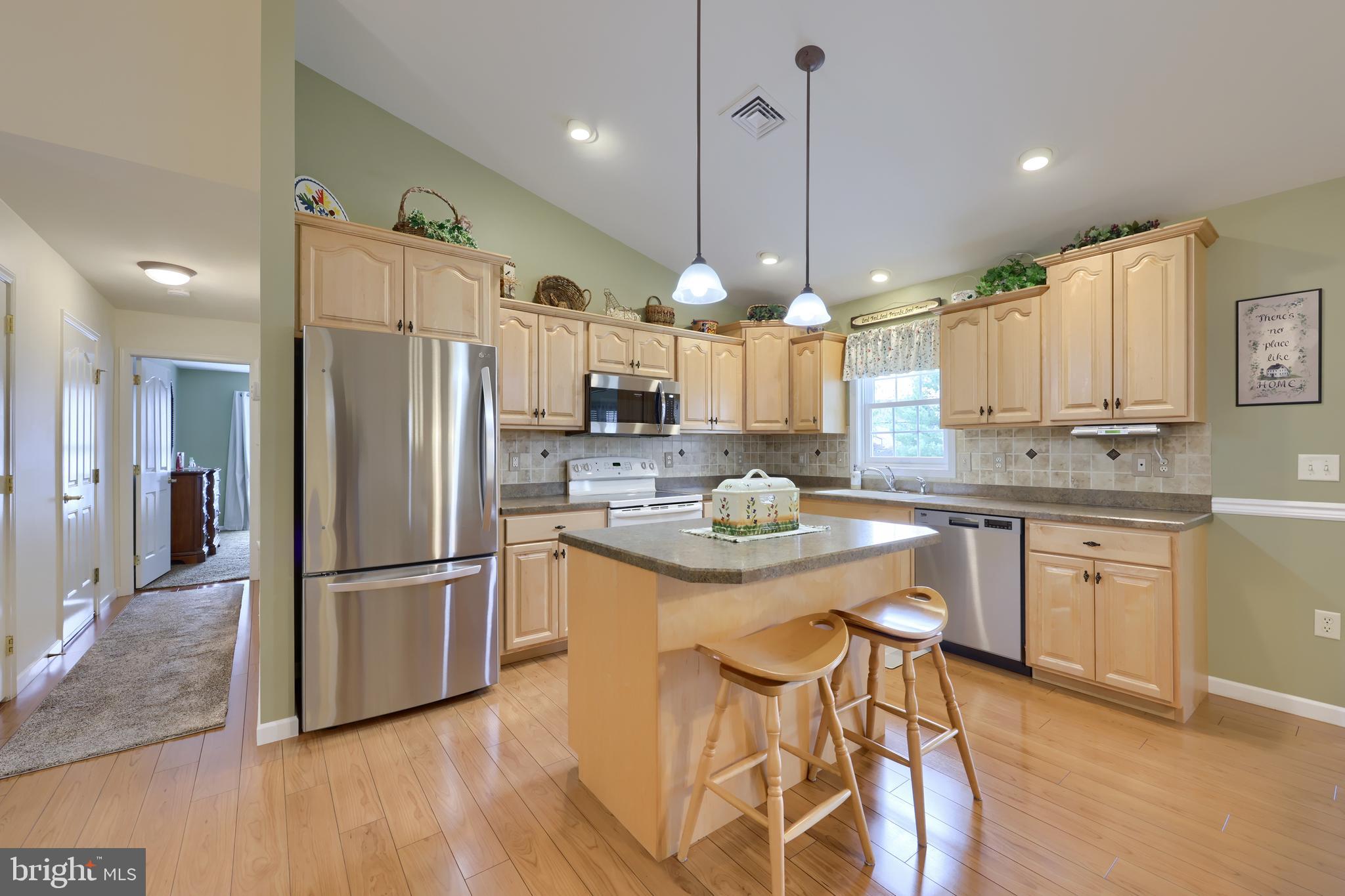 737 Heather Ridge Manheim, PA 17545 - Photo 17 of 40 a kitchen with stainless steel appliances kitchen island granite countertop a refrigerator a stove a sink and a dining table with wooden floor