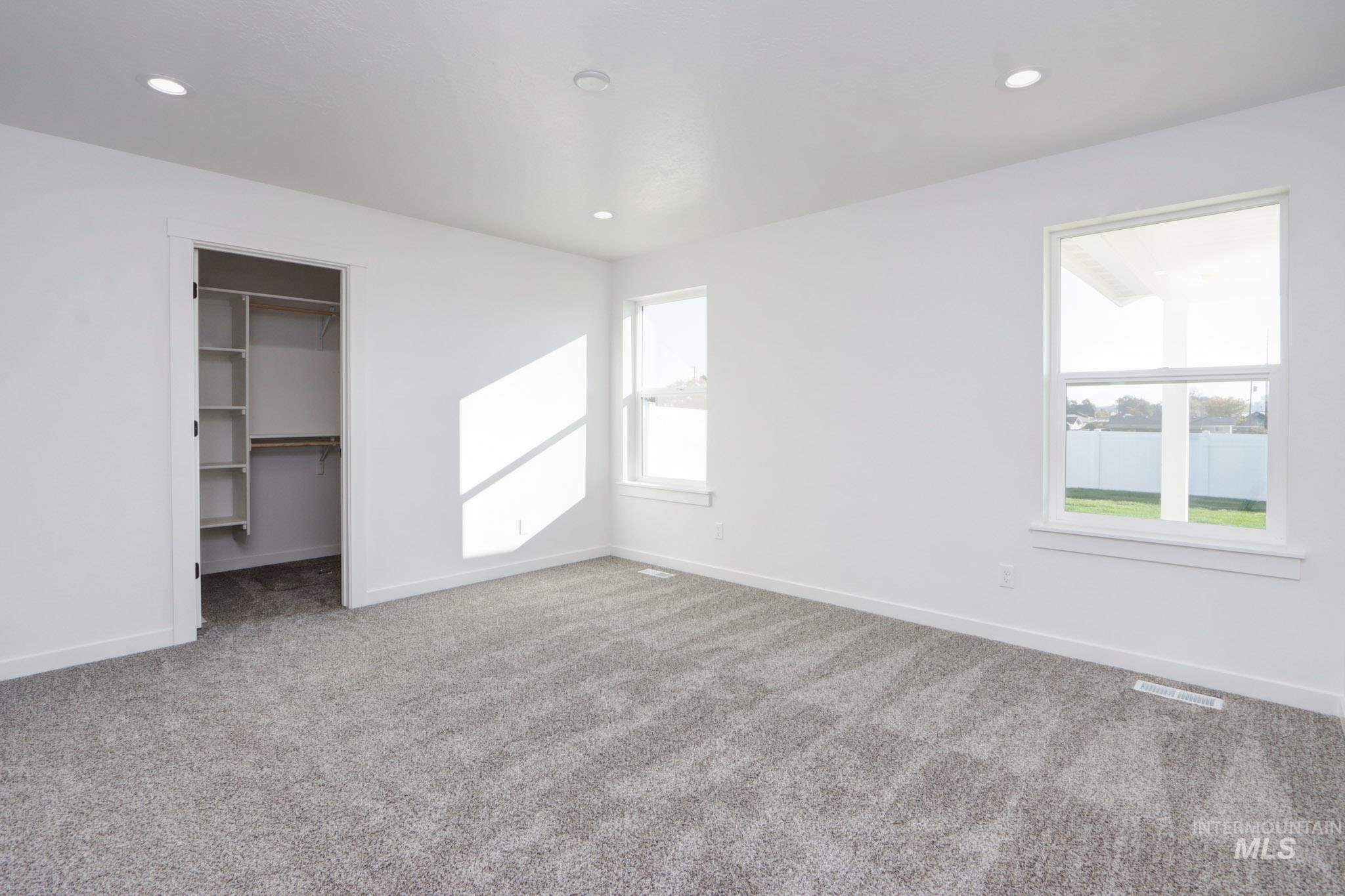 950 Campbell Street Vale, OR 97918 - Photo 16 of 37 Bright room featuring two windows, neutral wall paint, recessed lighting, patterned carpet, and a closet with built-in shelving