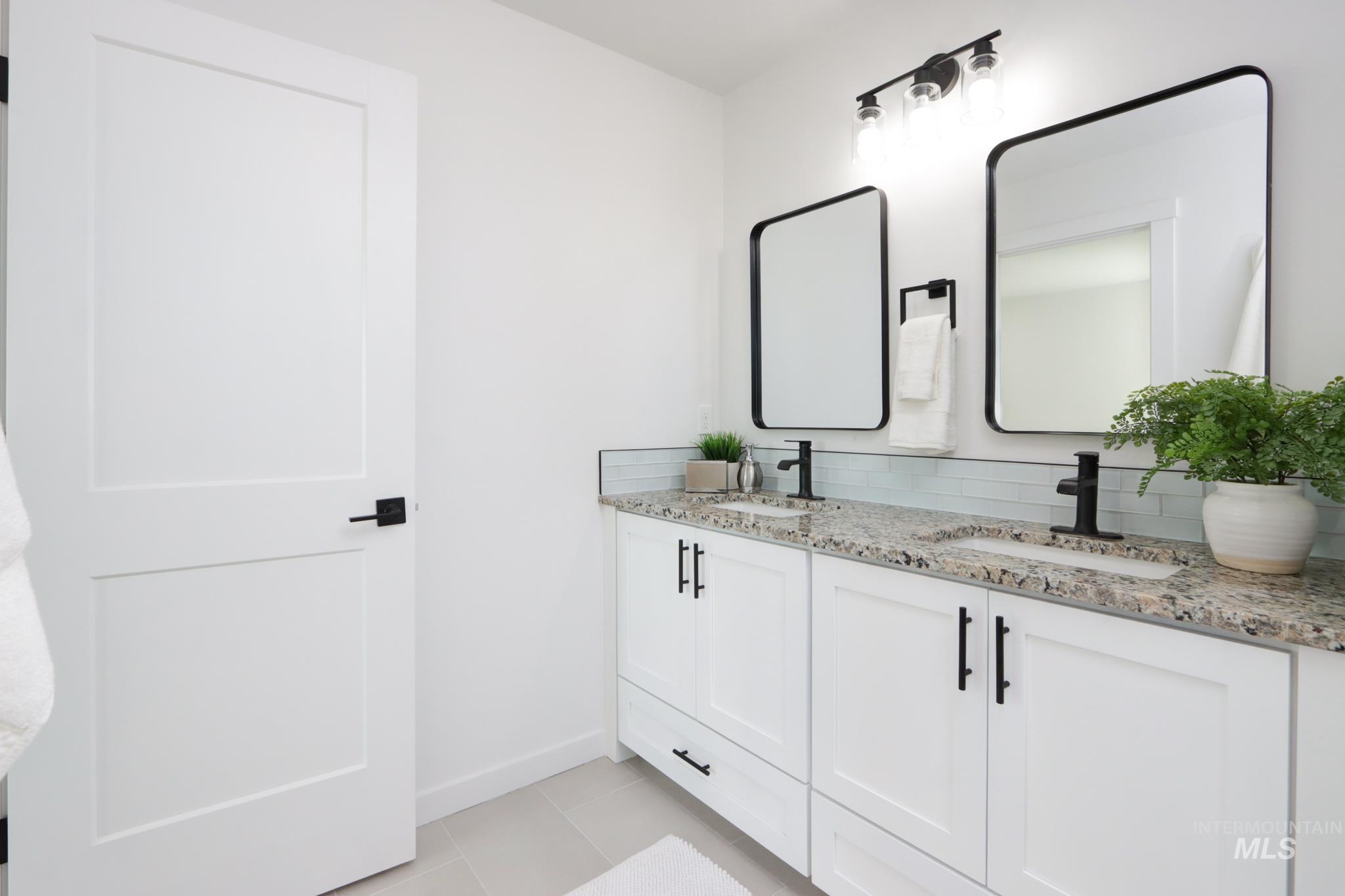 950 Campbell Street Vale, OR 97918 - Photo 23 of 37 Dual vanity featuring white shaker cabinetry with black hardware, stone-finish countertops, undermount sinks with matte black faucets, and rectangular framed mirrors