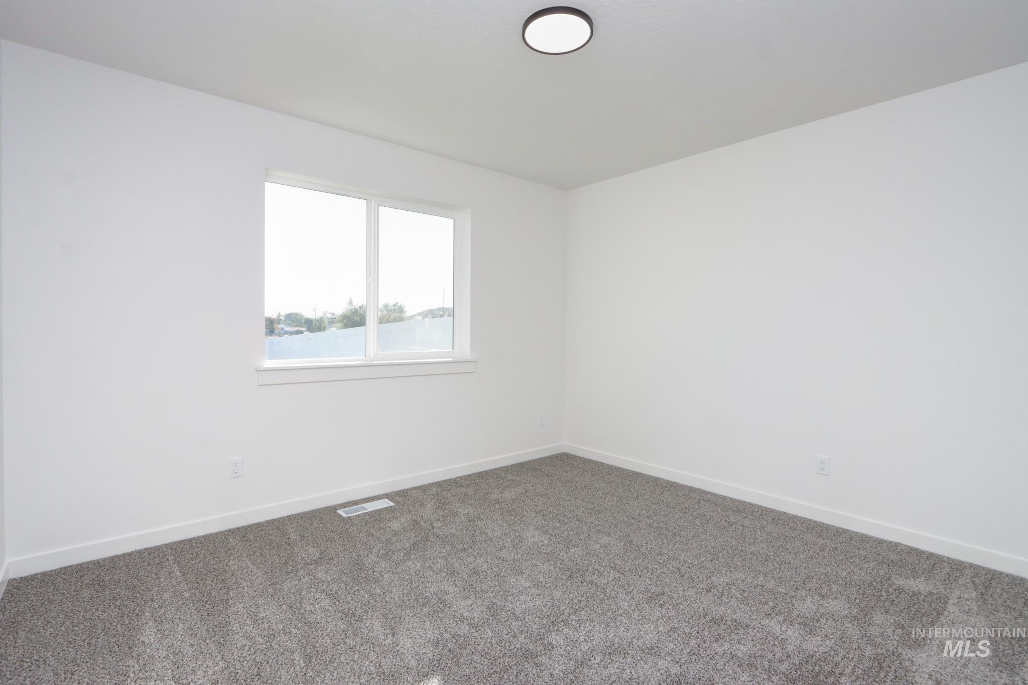 950 Campbell Street Vale, OR 97918 - Photo 25 of 37 Neutral painted room featuring a double-pane window, gray carpet flooring, white baseboards, and a flush-mount ceiling light fixture