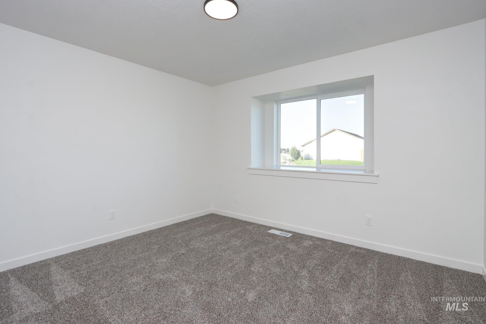 950 Campbell Street Vale, OR 97918 - Photo 28 of 37 Bright interior space featuring a double-pane window, flush-mount ceiling light, white baseboards, and neutral-toned carpet flooring