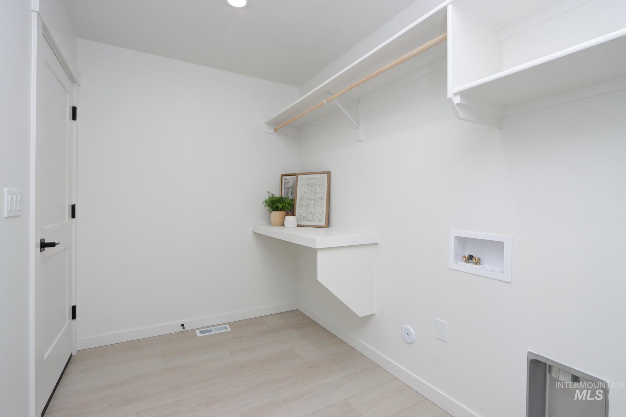950 Campbell Street Vale, OR 97918 - Photo 30 of 37 Dedicated laundry area featuring light wood-finish flooring, a built-in wall shelf, overhead shelving, and a hanging rod
