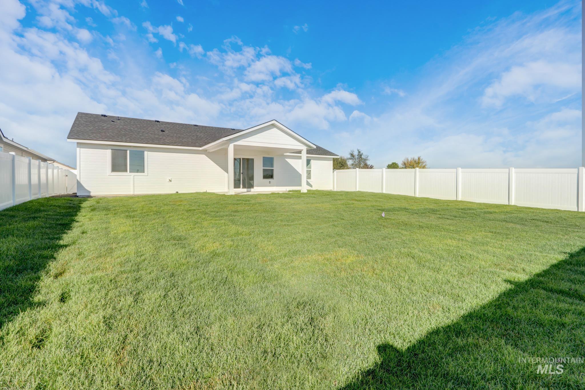 950 Campbell Street Vale, OR 97918 - Photo 33 of 37 Expansive backyard featuring a manicured lawn, full vinyl privacy fencing, and a covered patio with sliding glass door access