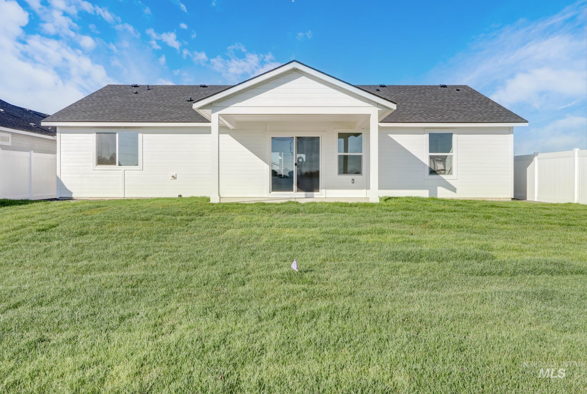 950 Campbell Street Vale, OR 97918 - Photo 35 of 37 Expansive backyard featuring a lush lawn, white vinyl fencing, a covered patio, and dual-pane windows