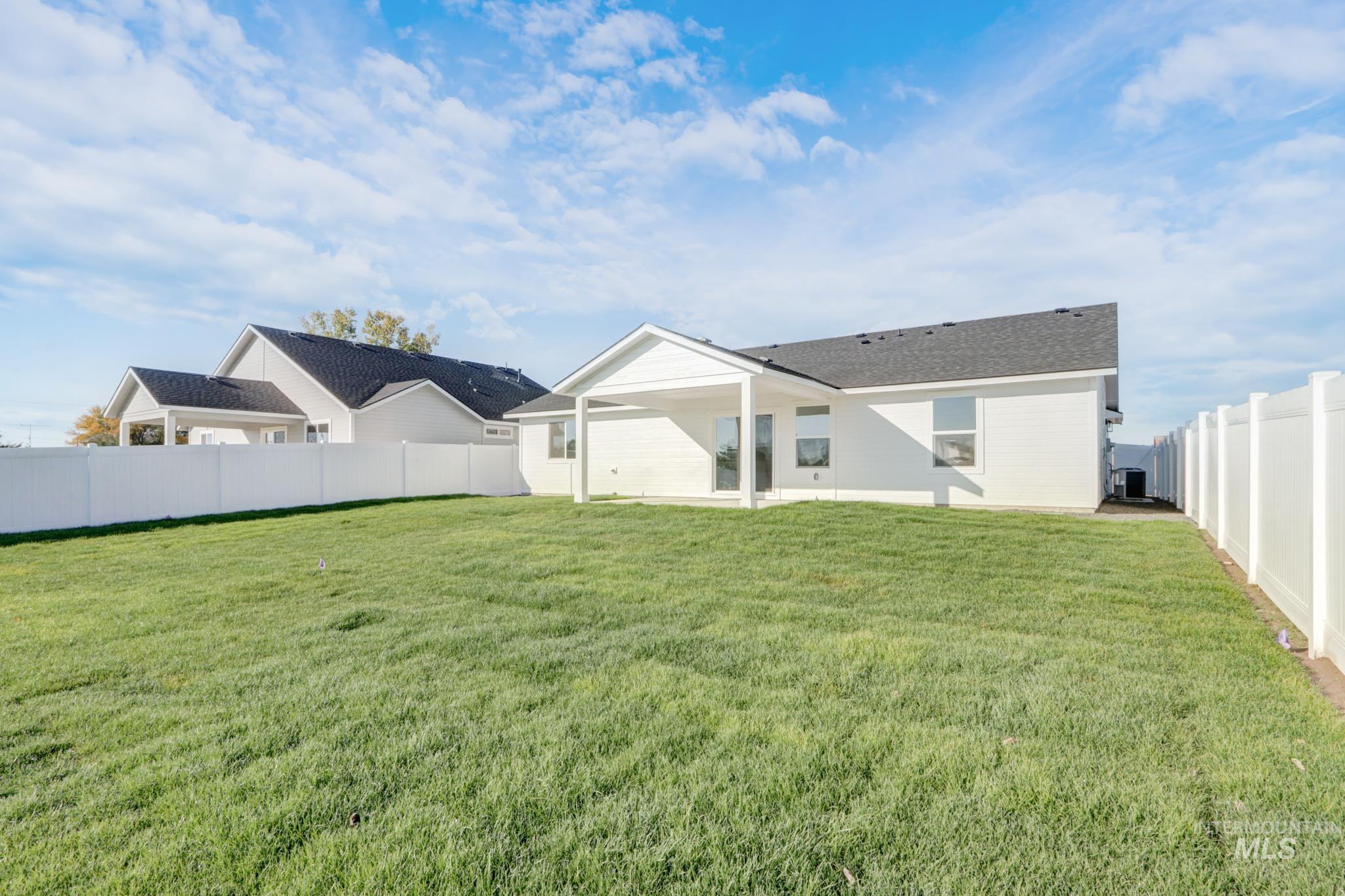 950 Campbell Street Vale, OR 97918 - Photo 36 of 37 Expansive backyard featuring a lush lawn, white vinyl fencing, and a covered patio area with a white exterior