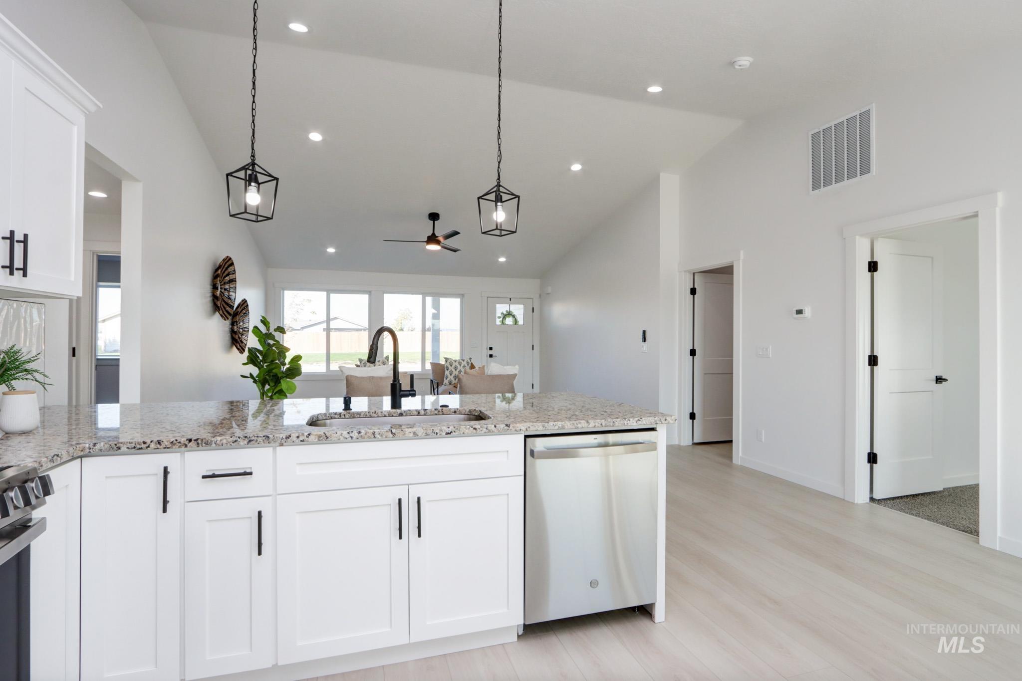950 Campbell Street Vale, OR 97918 - Photo 6 of 37 Kitchen island featuring a granite-style countertop, undermount sink with a matte black faucet, white shaker-style cabinetry, and a stainless steel dishwasher
