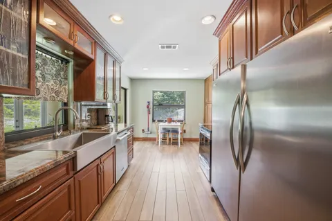 a kitchen with stainless steel appliances granite countertop a refrigerator a sink a stove and a wooden floors