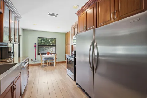 a kitchen with stainless steel appliances granite countertop a refrigerator a stove and a wooden cabinets