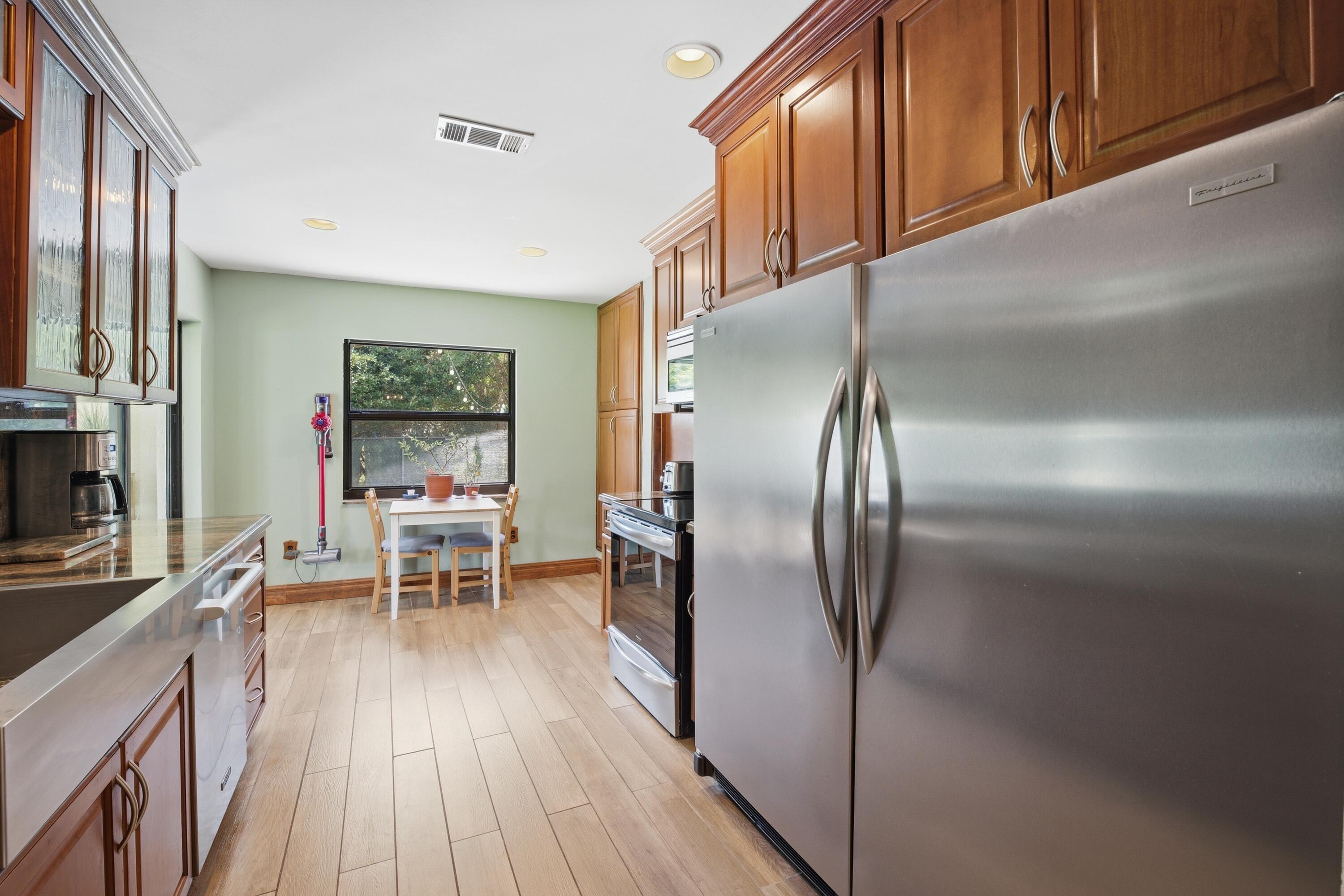 22504 Southwest 65th Avenue Boca Raton, FL 33428 - Photo 12 of 36 a kitchen with stainless steel appliances granite countertop a refrigerator a stove and a wooden cabinets