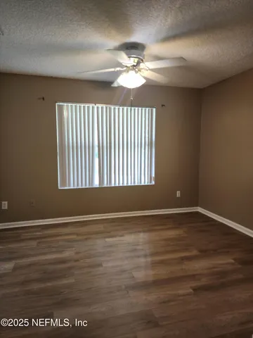a view of an empty room with wooden floor and a chandelier