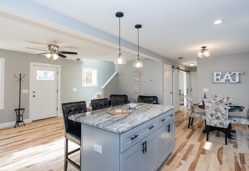 16 Cornflower Street Springfield, MA 01118 - Photo 12 of 36 a large kitchen with granite countertop a stove a sink a dining table and chairs with wooden floor