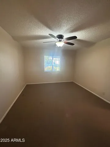 en empty room with windows and chandelier fan