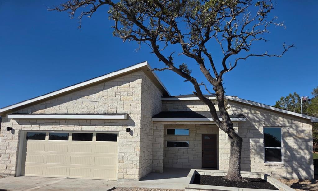 20008 Boggy Ford Road Lago Vista, TX 78645 - Photo 1 of 17 View of front facade with an attached garage, stone siding, and driveway