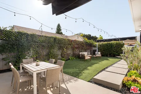 a view of a patio with table and chairs and potted plants with large tree