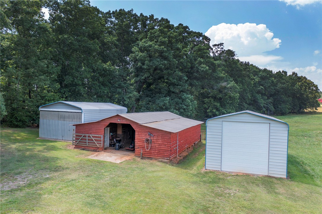 911 State Rd S-4-203 Belton, SC 29627 - Photo 46 of 49 A spacious yard provides ample room for two metal storage sheds and a red barn, ideal for various uses.
