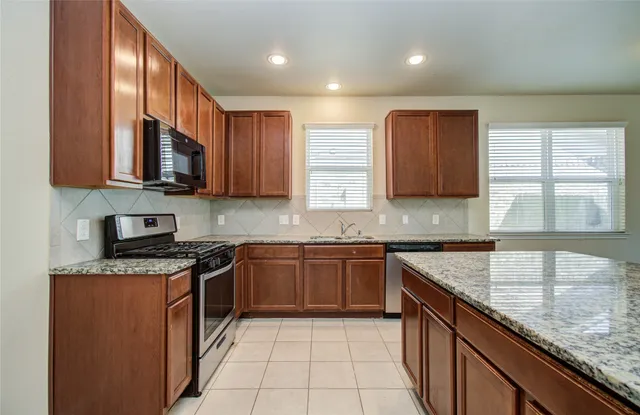a kitchen with kitchen island granite countertop stainless steel appliances and sink