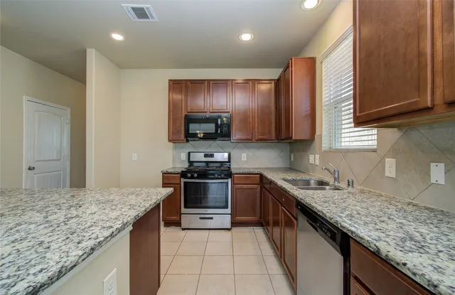 a large kitchen with stainless steel appliances granite countertop a refrigerator and a stove top oven
