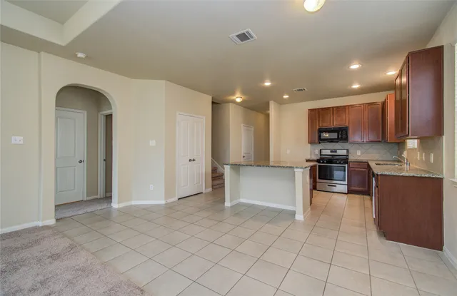 a large kitchen with a large counter top stainless steel appliances and cabinets