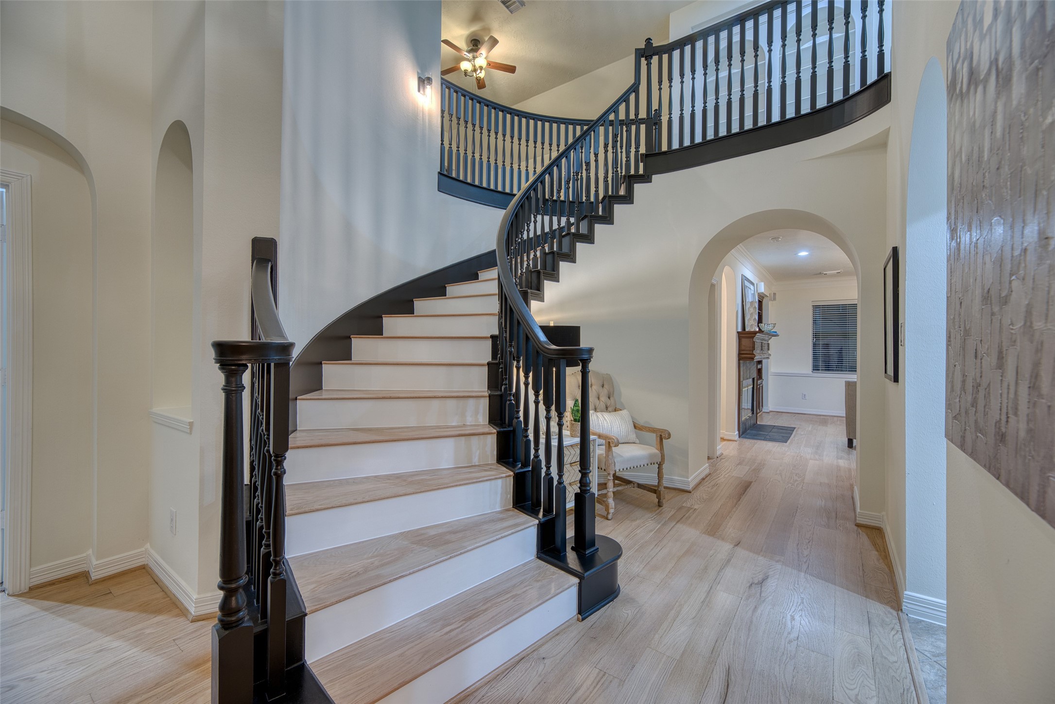 Stunning curved staircase with contrasting black railings and wood treads serves as a striking focal point in the entryway.