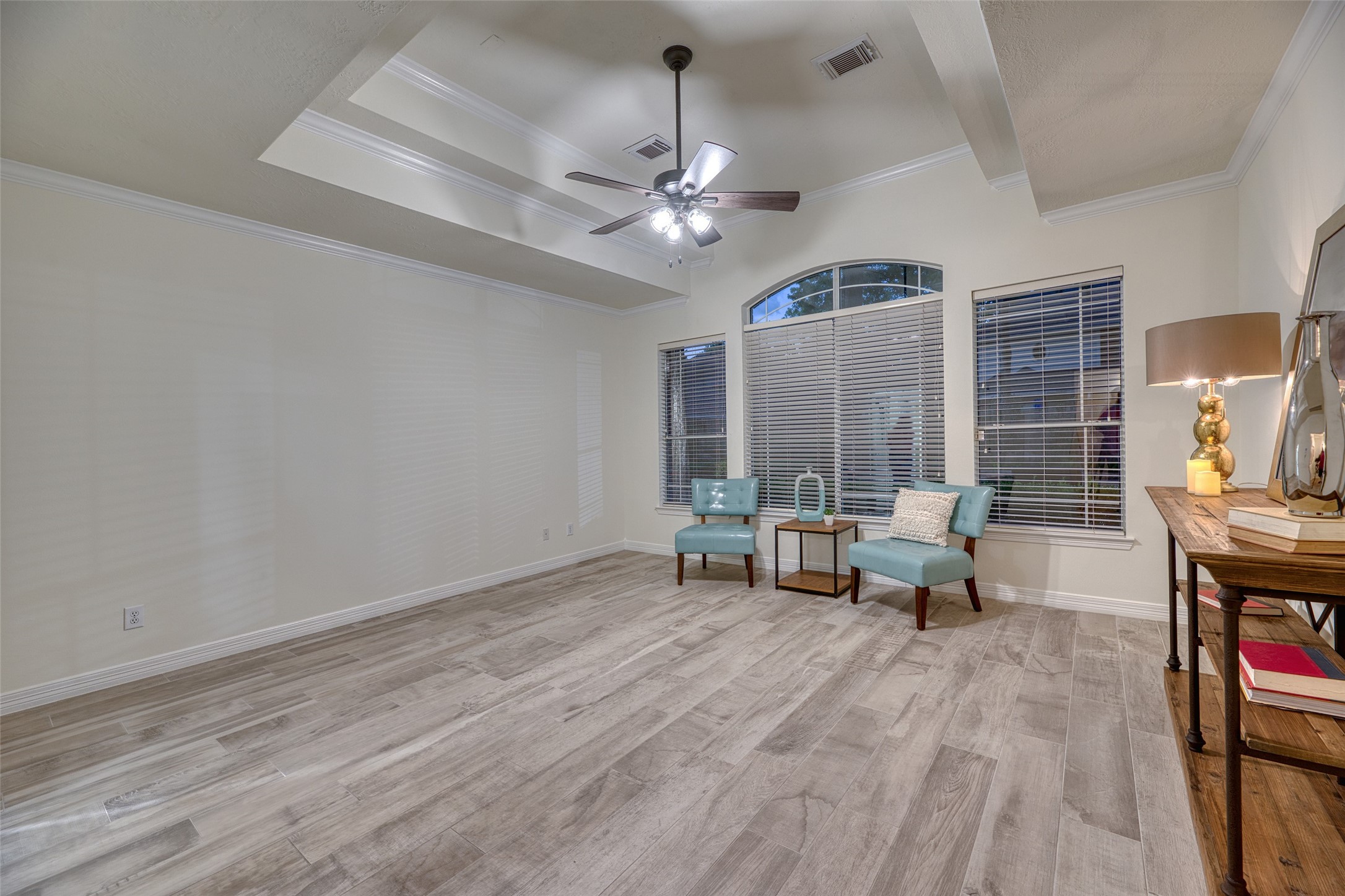 911 Chisel Point Drive Houston, TX 77094 - Photo 19 of 50 Generously sized primary suite with tray ceiling, crown molding, and wood-look tile flooring. Large windows provide views of the backyard.