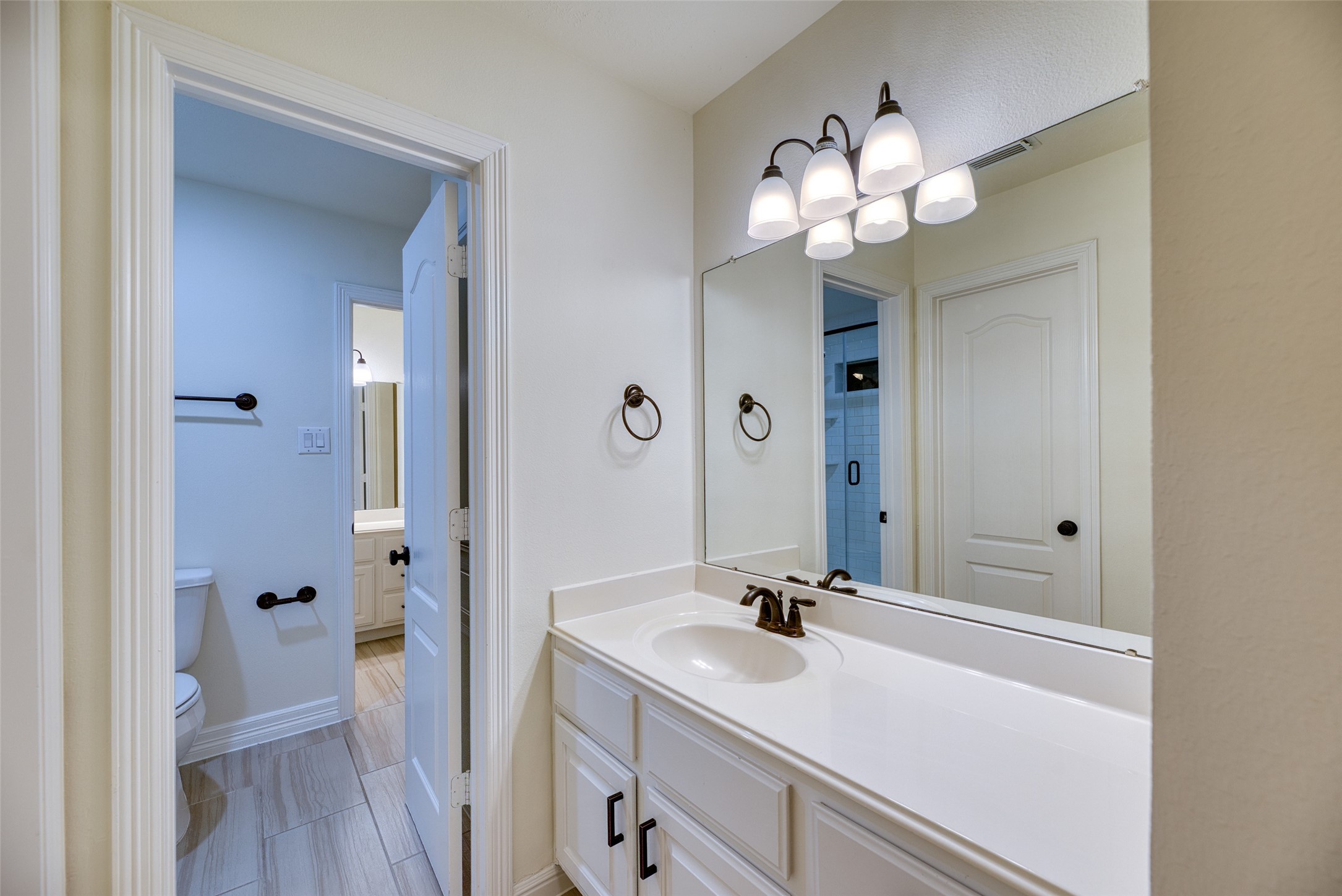911 Chisel Point Drive Houston, TX 77094 - Photo 30 of 50 Jack-and-Jill style vanity with white cabinetry, updated lighting, and access to shared bath.