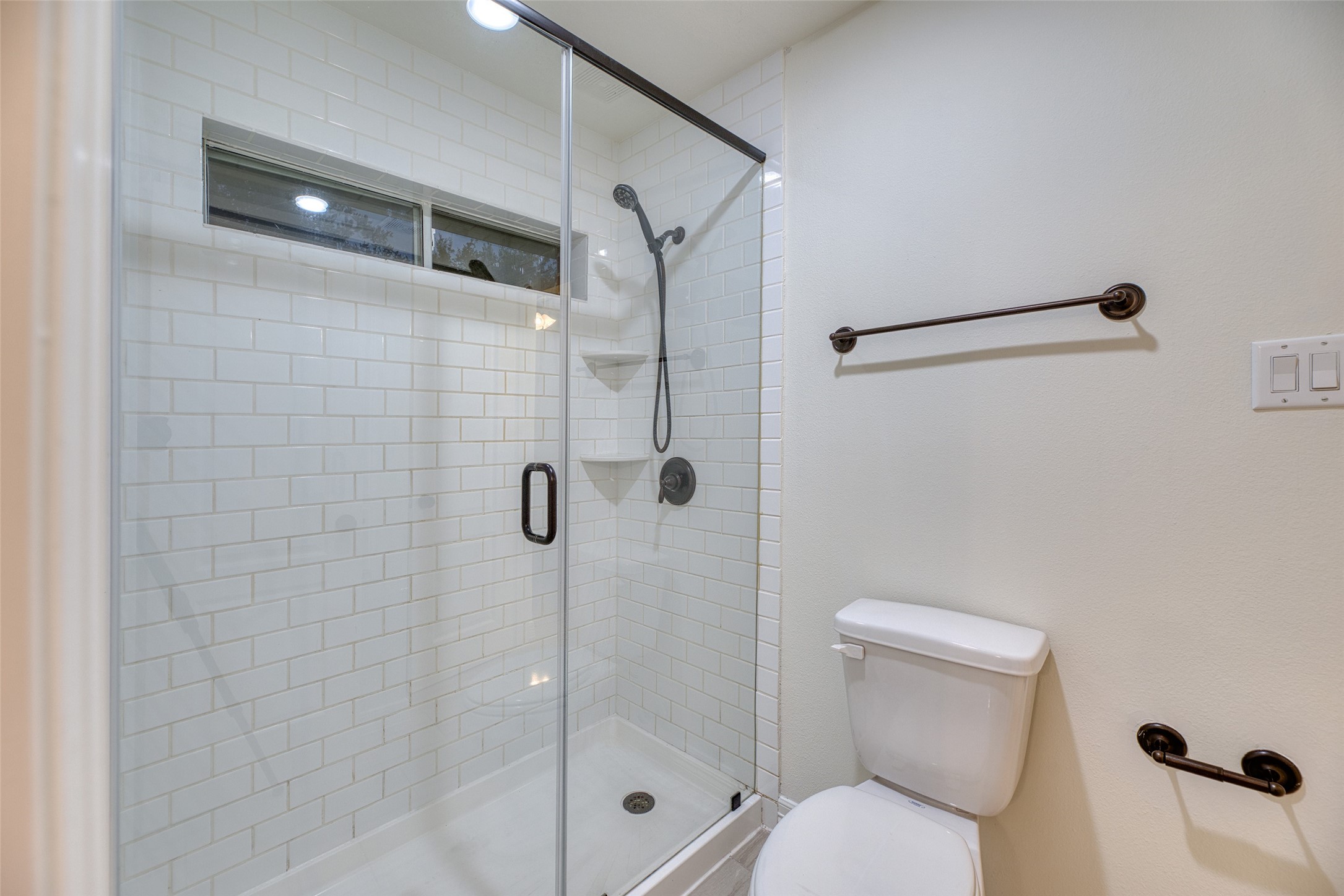 911 Chisel Point Drive Houston, TX 77094 - Photo 31 of 50 Modern walk-in shower with frameless glass enclosure, subway tile surround, and built-in corner shelves.