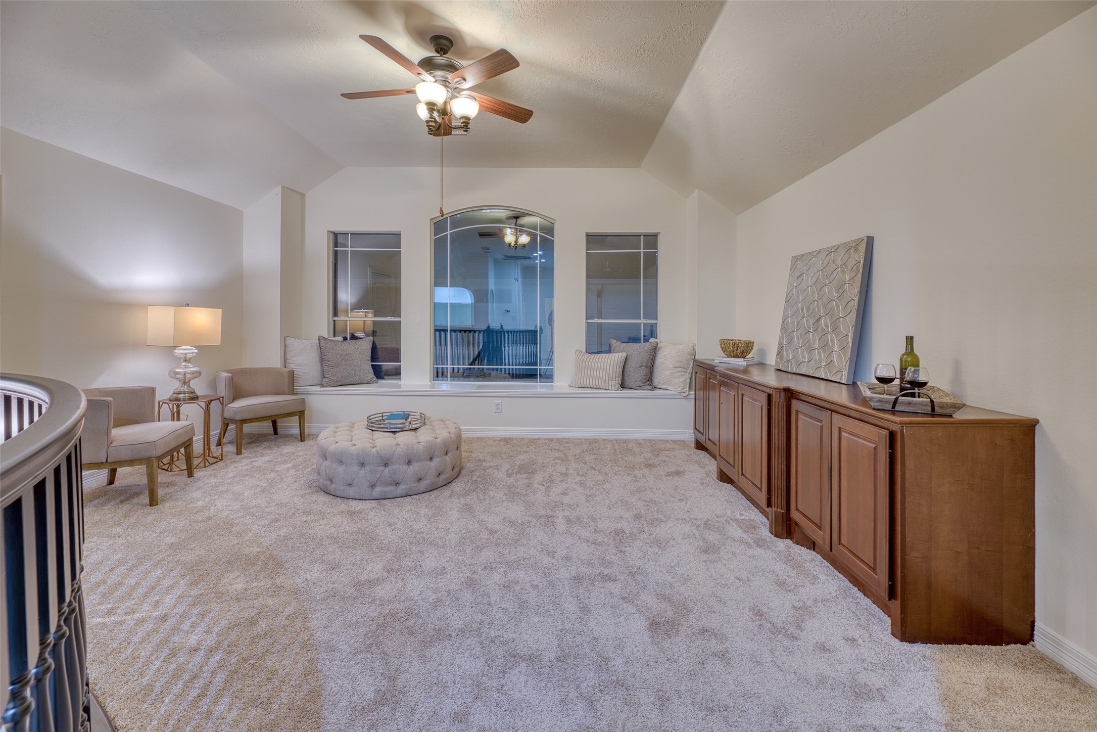 911 Chisel Point Drive Houston, TX 77094 - Photo 37 of 50 This inviting upstairs loft offers a versatile space for relaxing or entertaining, featuring plush carpeting, a built-in window seat with cozy cushions, and ample cabinetry for storage. A ceiling fan and neutral palette create a comfortable, airy atmosphere perfect for a reading nook, game area, or media space.