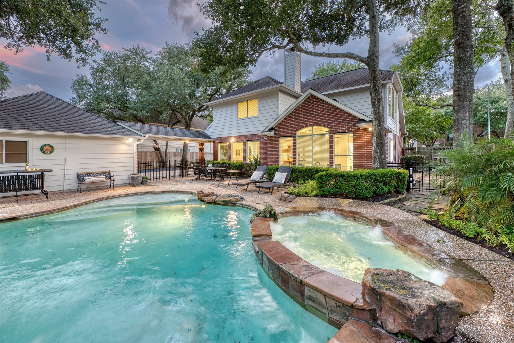 911 Chisel Point Drive Houston, TX 77094 - Photo 44 of 50 From this angle, the sparkling pool and elevated spa are showcased against the backdrop of the beautiful brick-and-siding two-story home. Multiple seating areas and a spacious patio make this the ultimate destination for relaxation and entertaining.